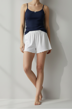 Person wearing a navy tank top and white shorts against a plain background