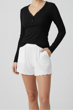 Person wearing a black long-sleeve top and white shorts on a light gray background